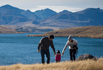 Family walking by lakeside with mountains in the background