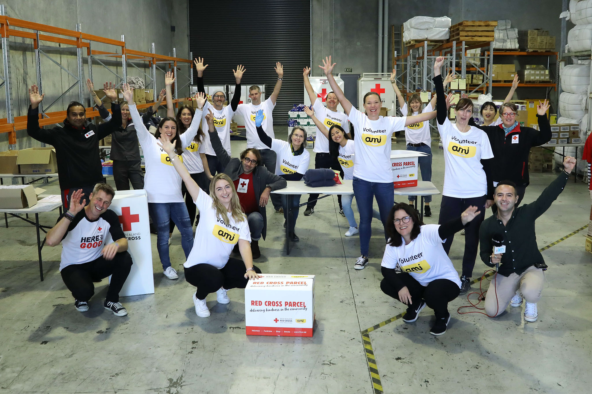 Group of people helping at the Red Cross charity posed to camera with hands raised